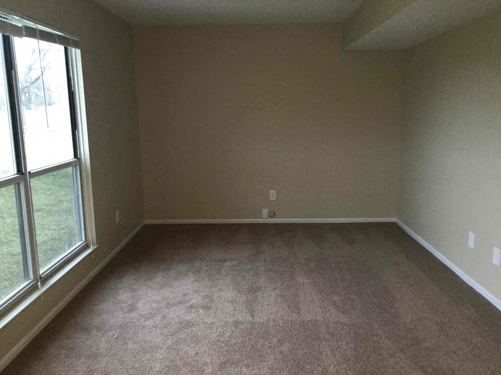 an empty living room with carpet and a large window