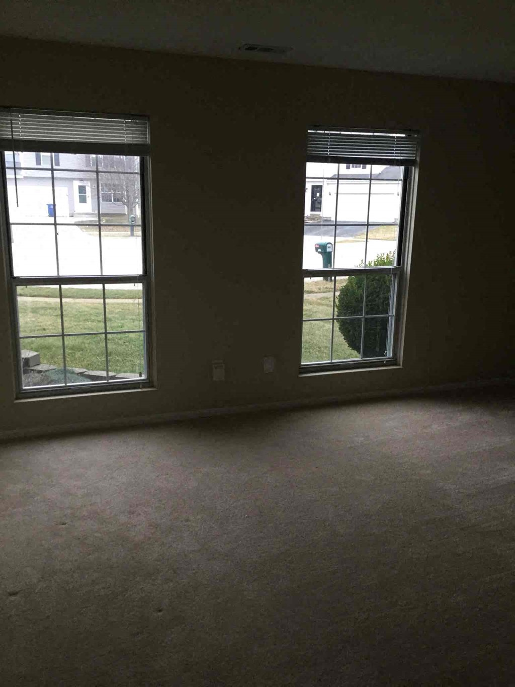 an empty living room with two large windows