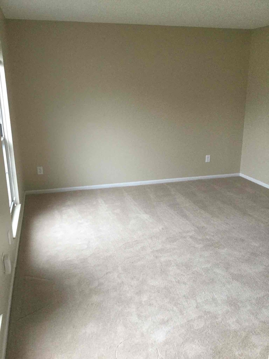 an empty living room with a carpeted floor