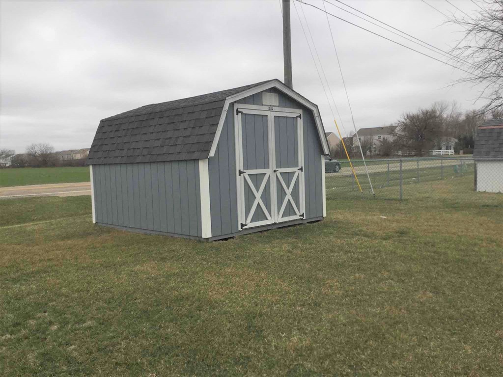 a small shed in the middle of a grass field