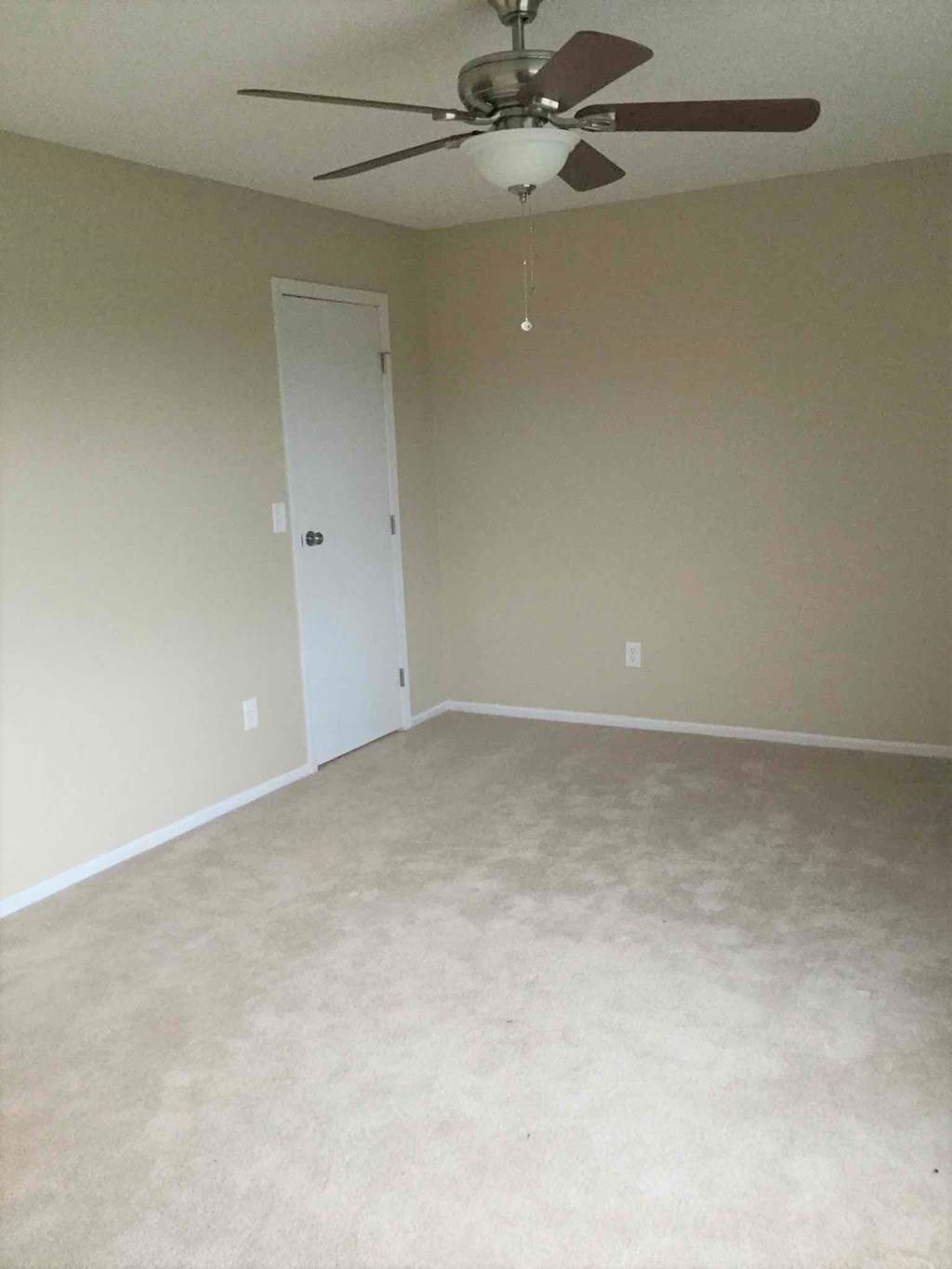 an empty living room with a ceiling fan