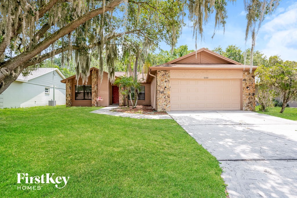 a home with a garage and a lawn and a tree