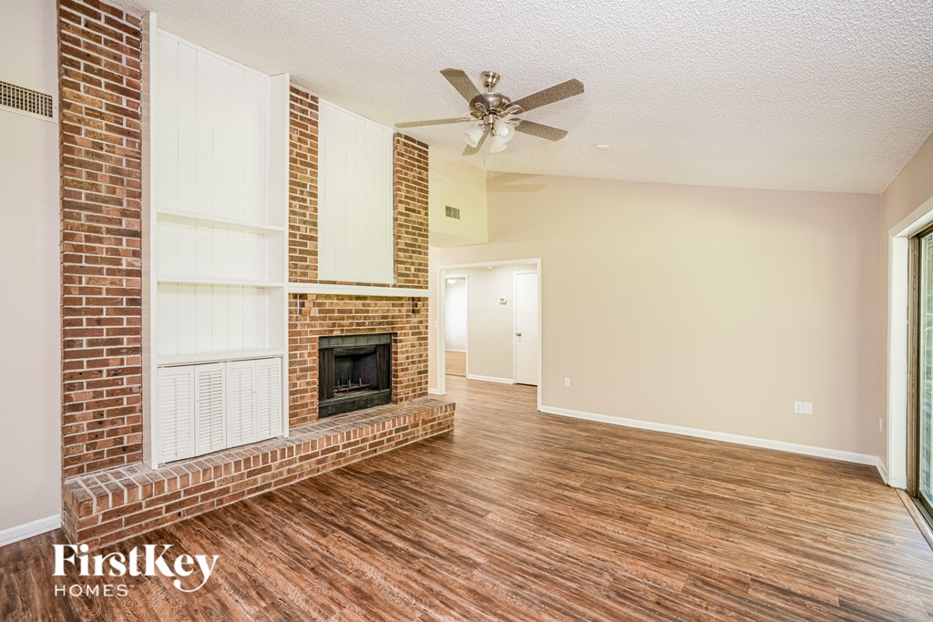 a living room with a brick fireplace and a ceiling fan