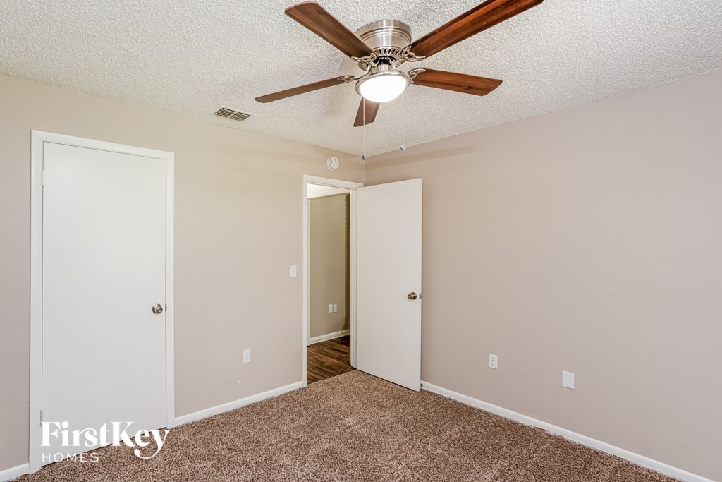 a bedroom with a ceiling fan and a door to a closet