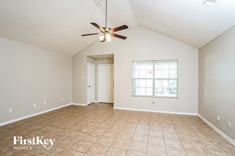 A spacious room with a ceiling fan and a window with blinds.