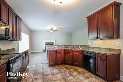 A kitchen with brown cabinets and a black dishwasher.