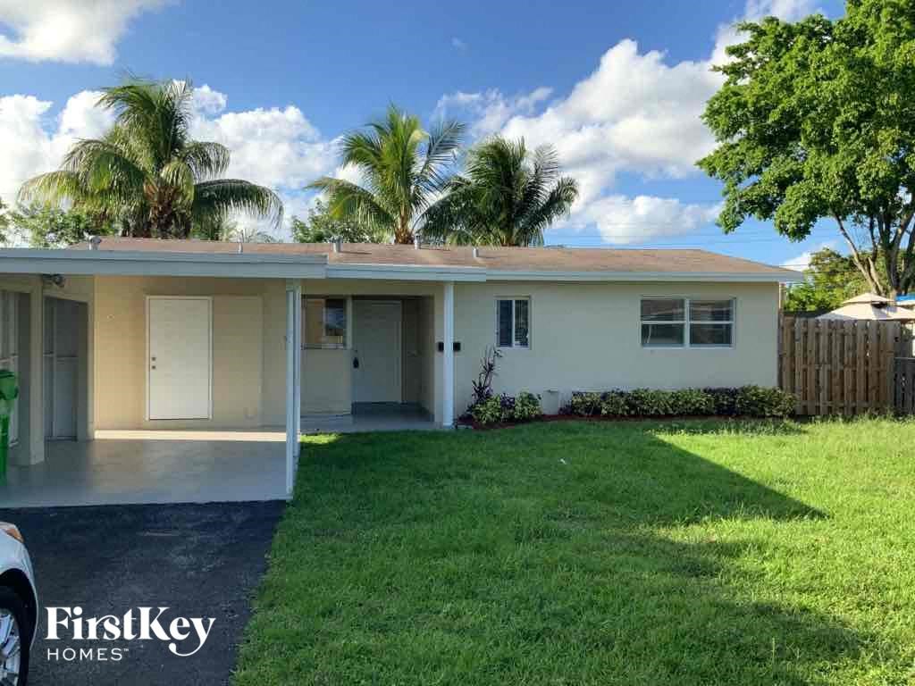 a small white house with a lawn and palm trees