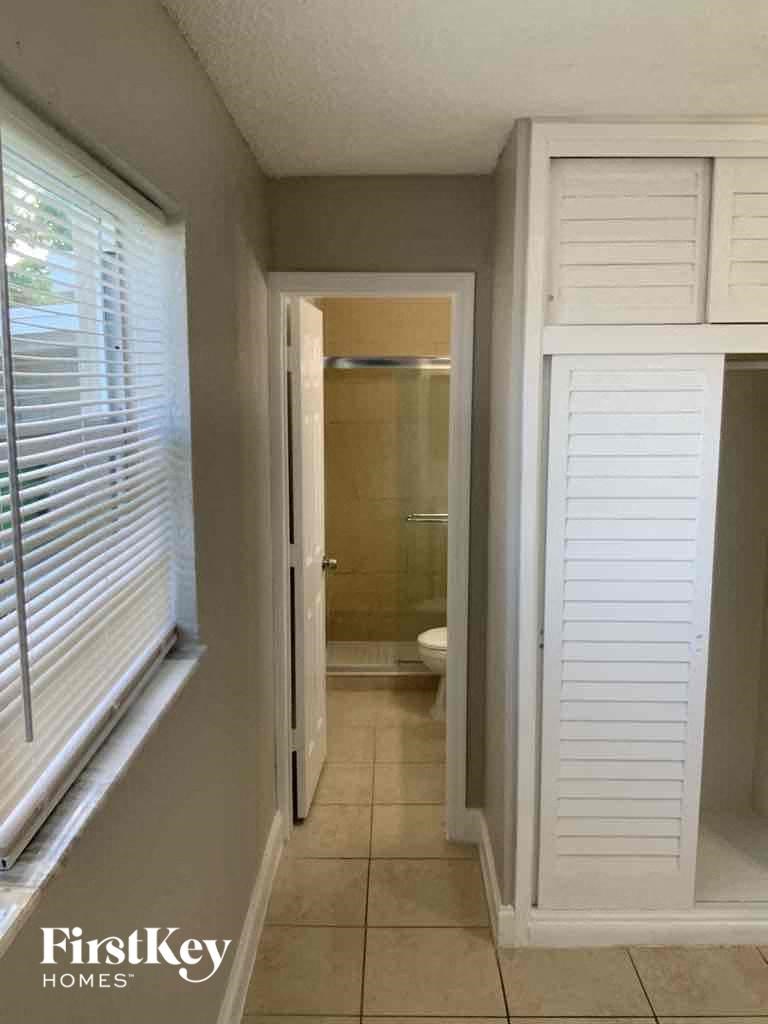 a view of a bathroom from a hallway with white shutters