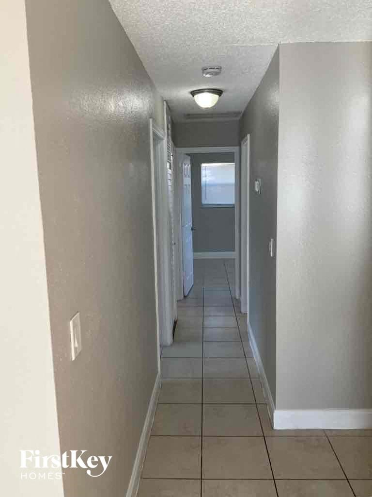 a hallway with a tiled floor and a door to a bedroom and a hallway