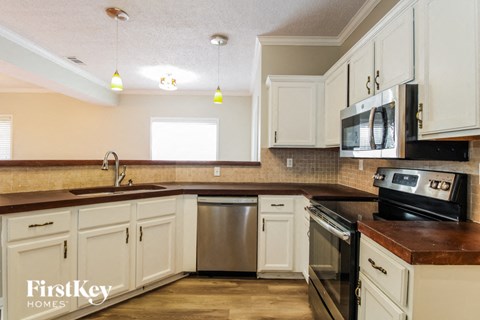 a kitchen with white cabinets and black appliances and a counter top