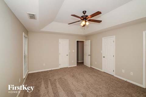 A spacious room with a ceiling fan and carpeted floor.