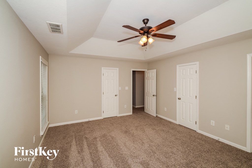 A spacious room with a ceiling fan and carpeted floor.