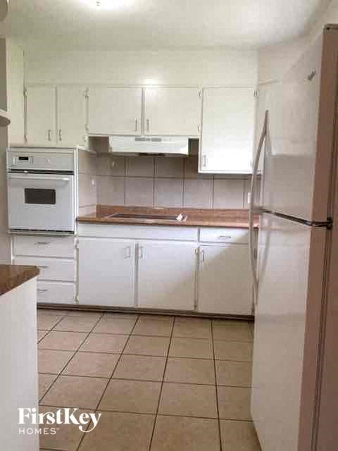 A kitchen with white cabinets and a refrigerator.