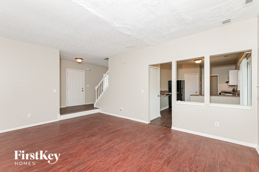 the living room and dining room with wood flooring and white walls