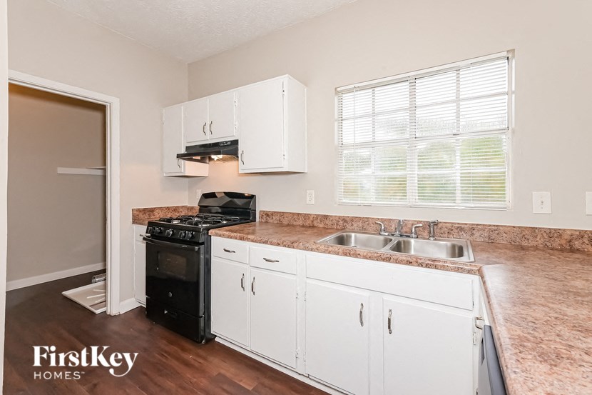 a kitchen with white cabinets and a black stove and sink