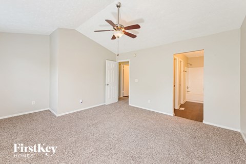 a spacious living room with carpet and a ceiling fan