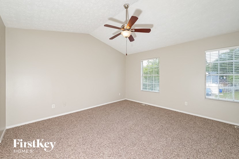 the master bedroom has a ceiling fan and a carpeted floor
