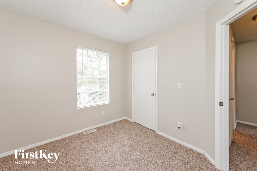 a bedroom with carpet and a door to a closet