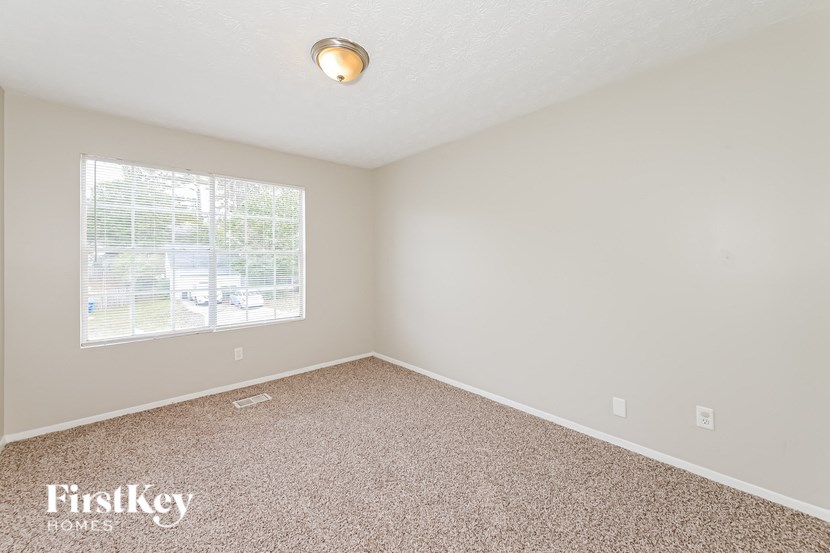 a bedroom with carpet and a large window