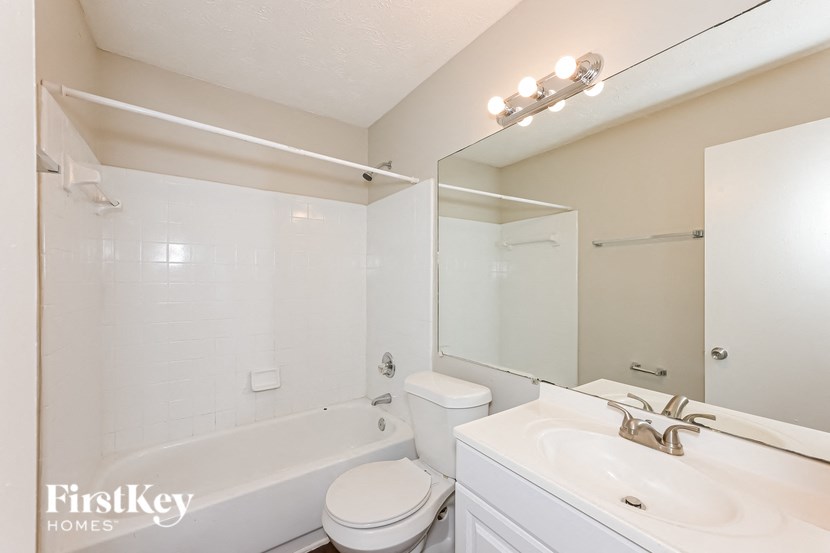 a bathroom with a tub sink and toilet and a mirror