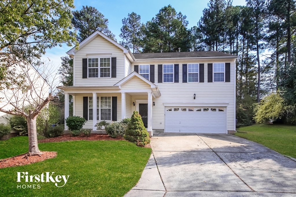 A white house with a black garage door is for sale.