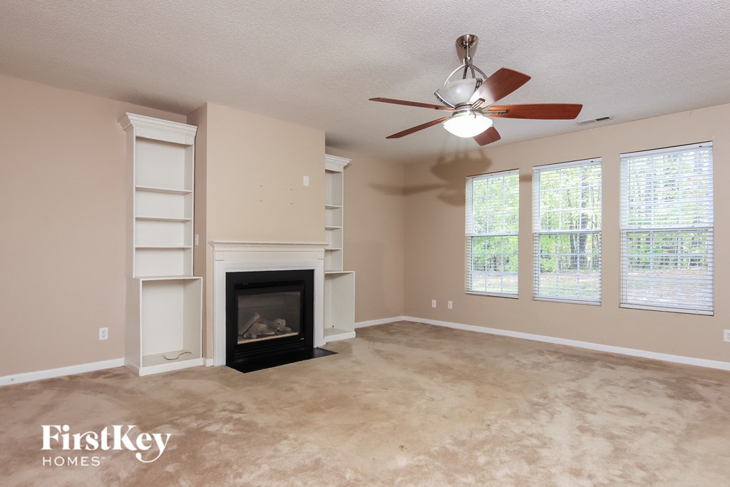 A living room with a fireplace and a ceiling fan.