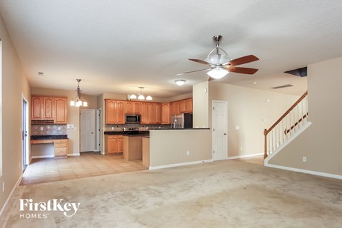 A spacious kitchen and living room with wooden cabinets and a staircase.