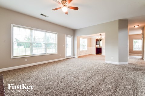 A spacious living room with a carpeted floor and a ceiling fan.