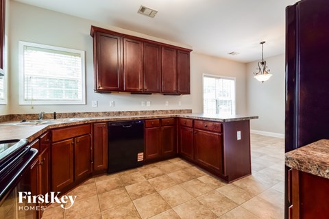 A kitchen with brown cabinets and a black dishwasher.