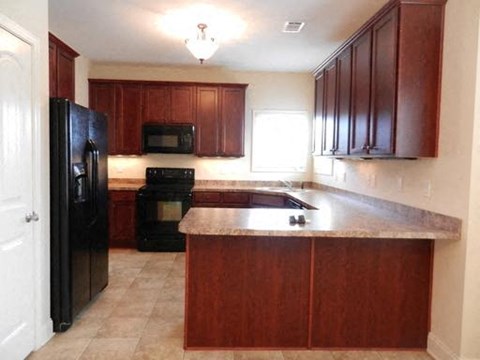 A kitchen with brown cabinets and black appliances.