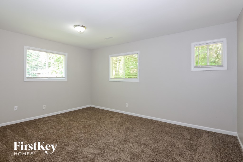a empty room with carpet and two windows