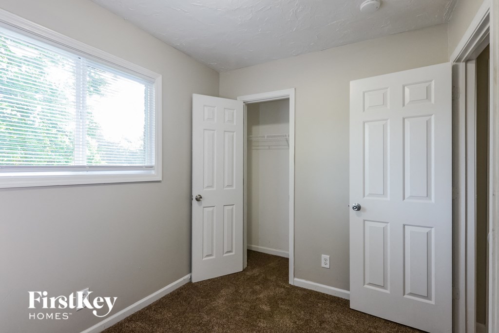 a bedroom with two doors and a window and a closet
