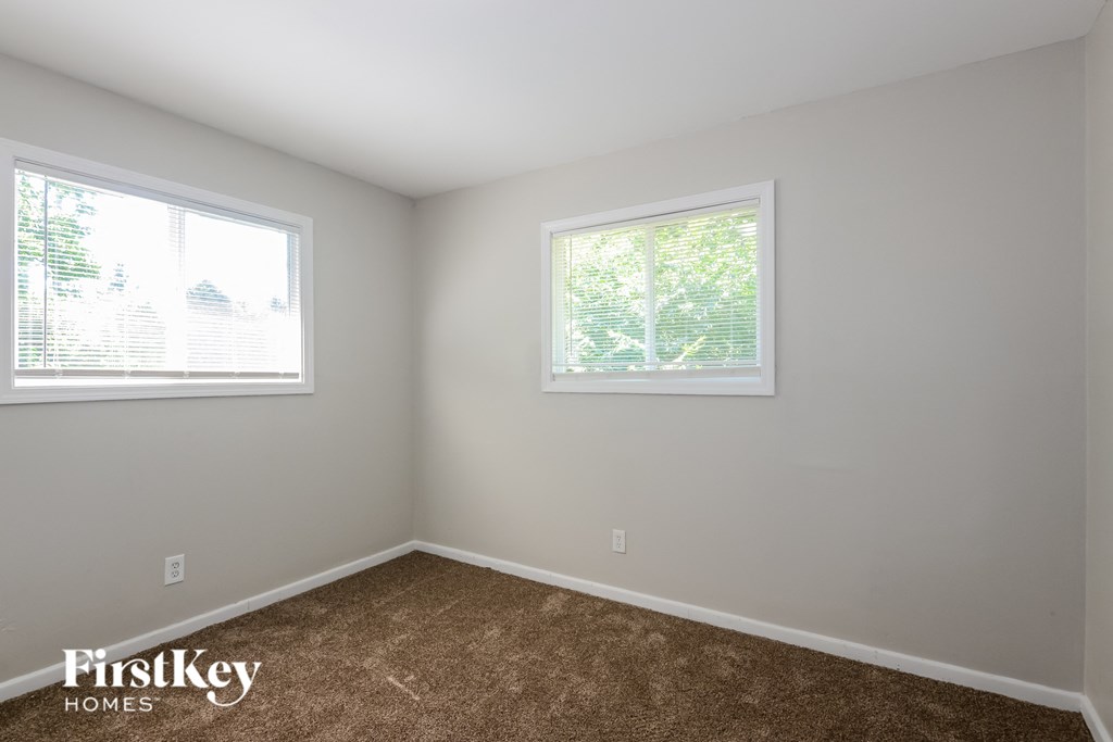 a bedroom with a carpeted floor and two windows
