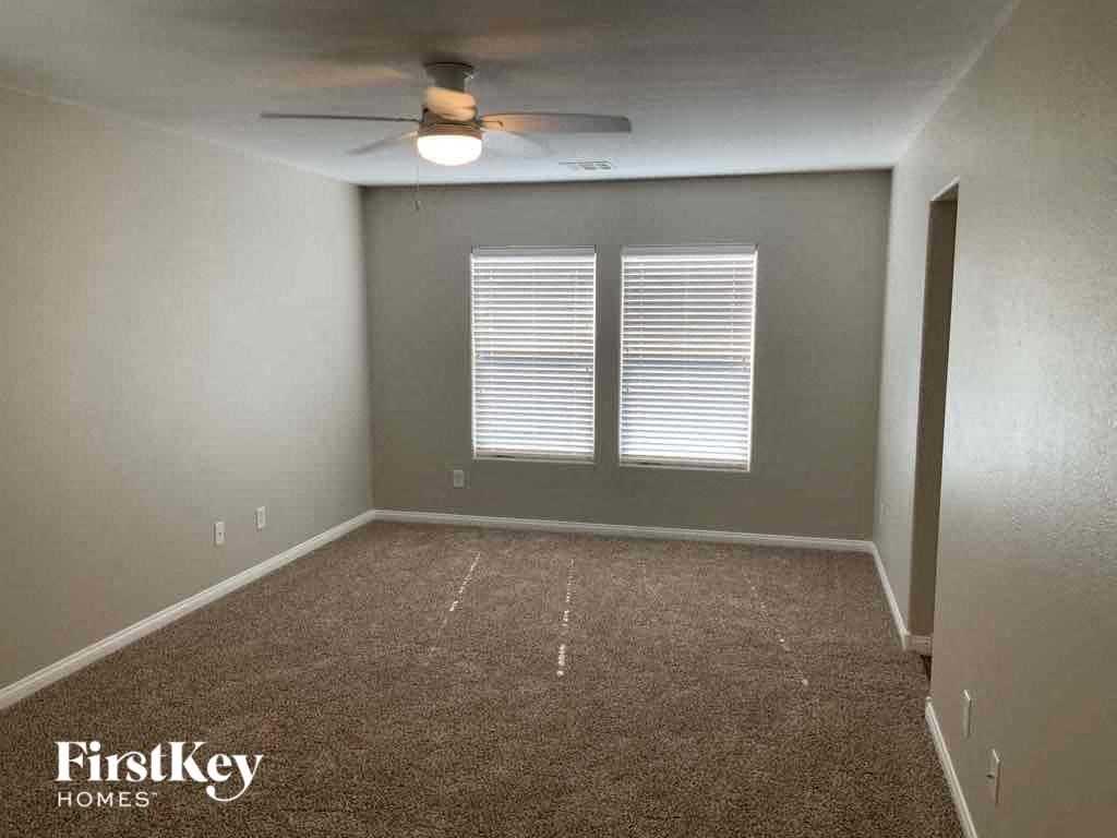 A room with a carpeted floor and a ceiling fan.