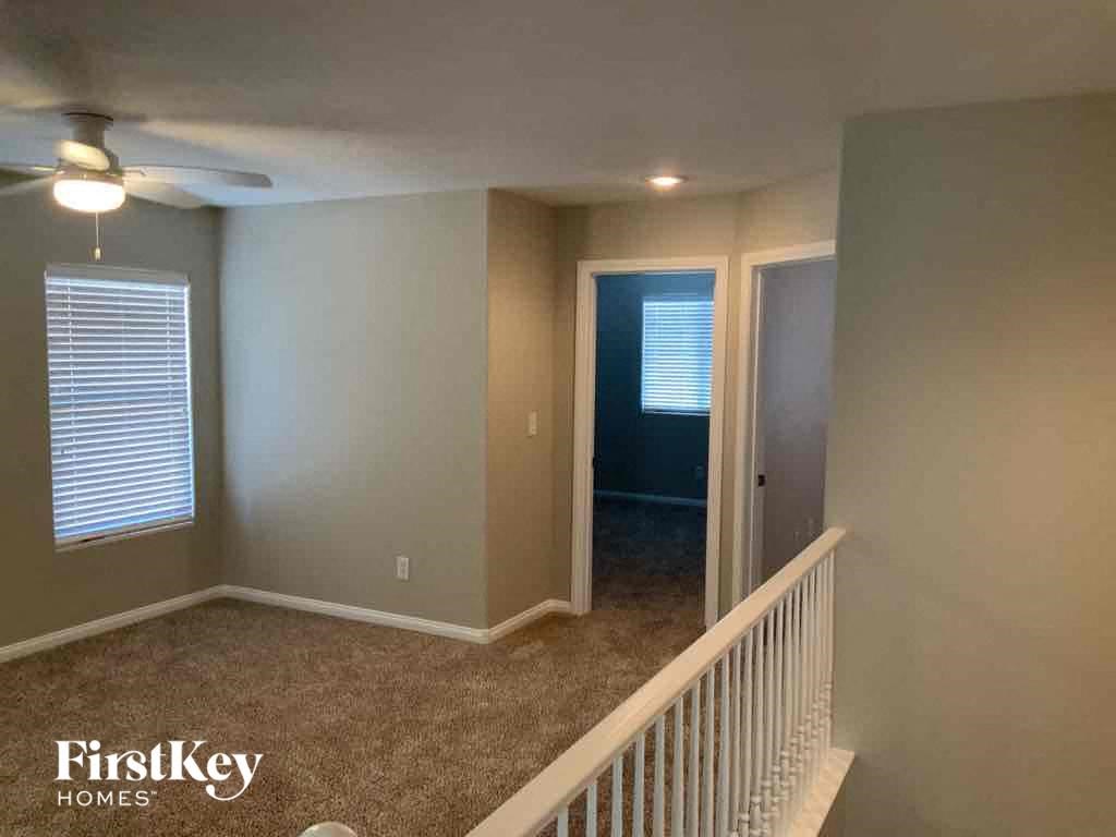 A room with a carpeted floor and a ceiling fan.