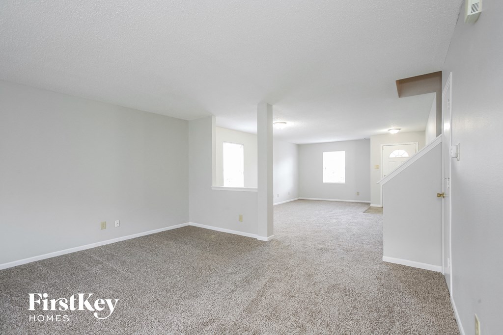 a spacious living room with carpet and white walls