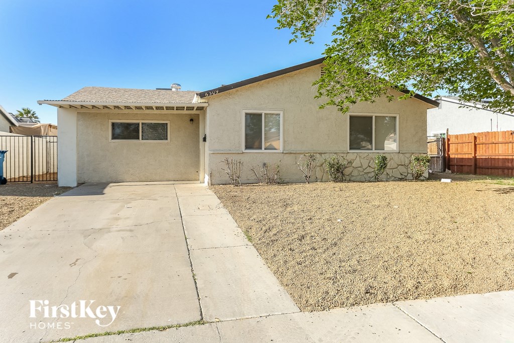 A small house with a brown roof and a white garage door is for sale.