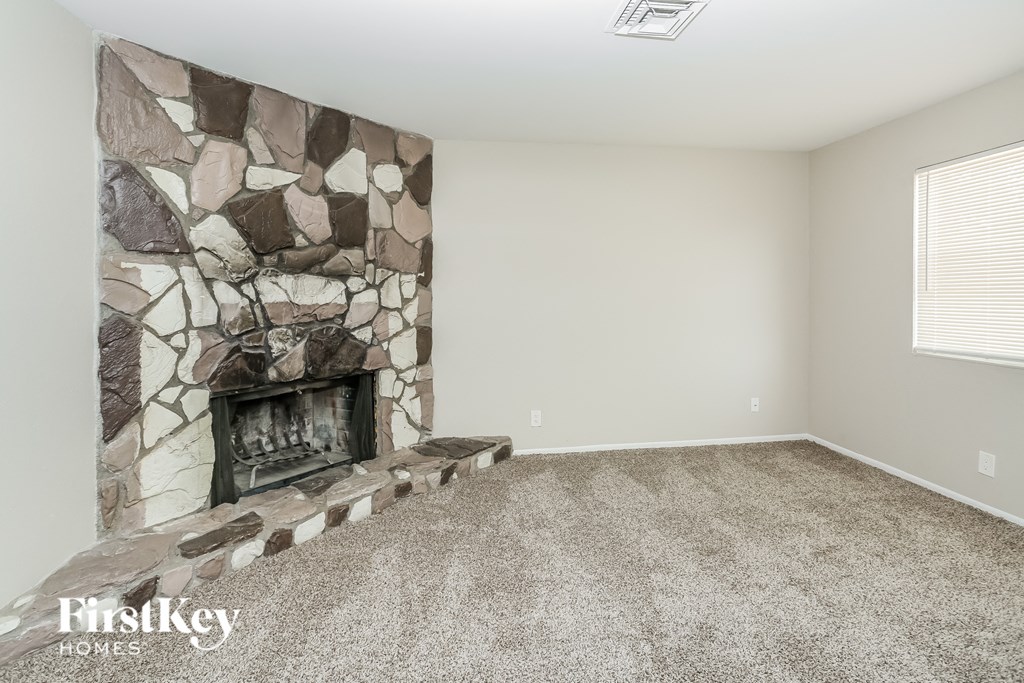 A room with a stone fireplace and a carpeted floor.