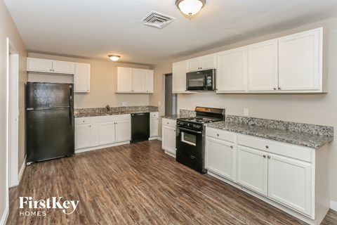 A kitchen with a black fridge, black oven, and white cabinets.
