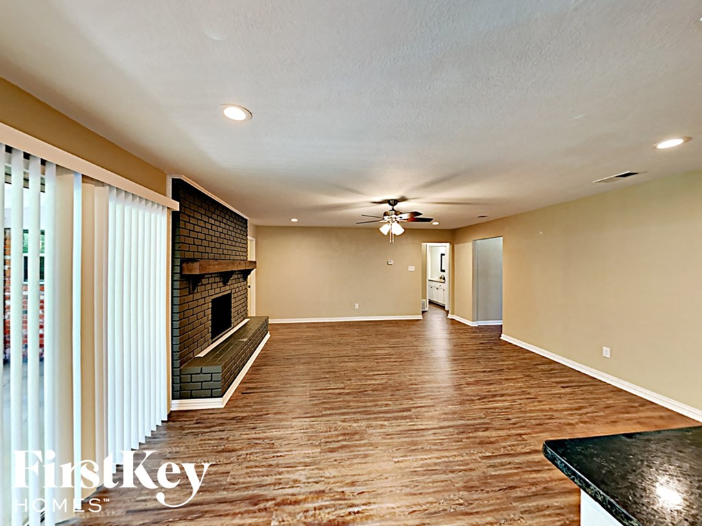 an empty living room with a fireplace and a ceiling fan