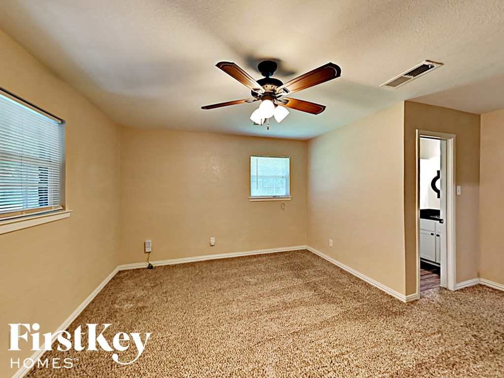 the master bedroom has a ceiling fan and a door to the bathroom