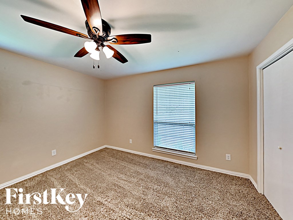 an empty bedroom with a ceiling fan and a window