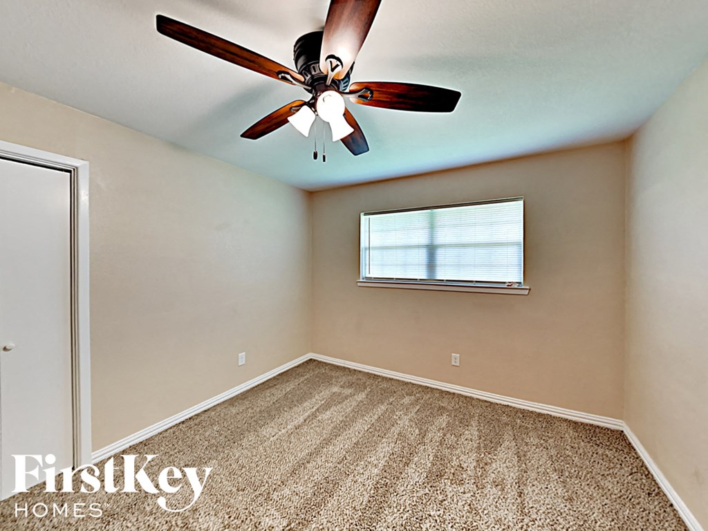 an empty bedroom with a ceiling fan and a window