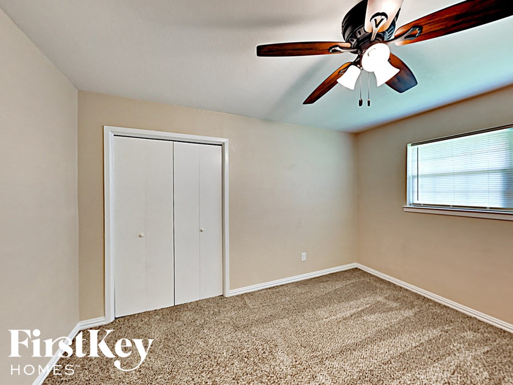 an empty bedroom with a ceiling fan and a closet