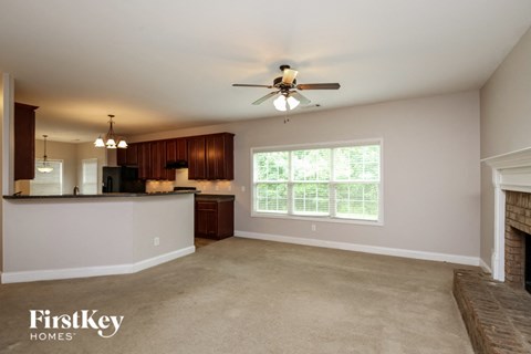 A spacious living room with a fireplace and a ceiling fan.