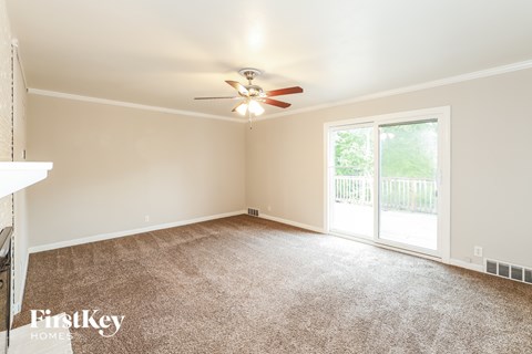 A room with a carpet floor and a ceiling fan.