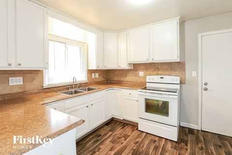 A kitchen with white cabinets and a white stove top oven.