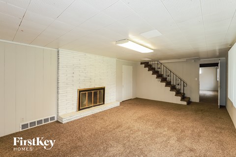 A spacious room with a fireplace and a staircase.