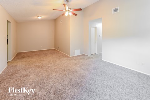 A spacious room with a ceiling fan and carpeted floor.