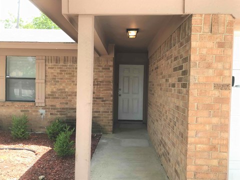 a front porch of a brick house with a white door